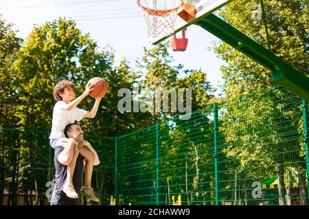 Homme tenant un petit garçon sur les épaules, jouant au basket-ball Banque D'Images