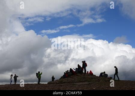 Un groupe de randonneurs se voit photographier à côté d'une plaque au sommet de la montagne de Pen y Fan, dans le parc national de Brecon Beacons, au pays de Galles. APPUYEZ SUR ASSOCIATION photo. Date de la photo: Mardi 12 juillet 2016. Le crédit photo devrait se lire: Yui Mok/PA Wire Banque D'Images