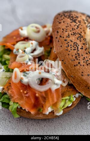 Bagel au saumon avec fromage à la crème, herbes fraîches et légumes sur un comptoir en marbre Banque D'Images