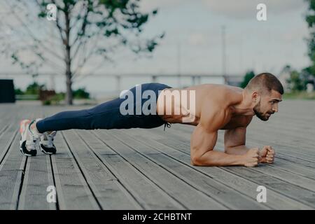 Un athlète masculin motivé fait de l'exercice abs, aime l'entraînement de culturisme en extérieur et se tient en planche. Un homme adulte européen fort et musclé a une forme physique Banque D'Images