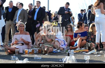 Racegoers assis sur le sol, de mesdames Jour du Grand Festival National de Santé Randox à Aintree Racecourse. Banque D'Images