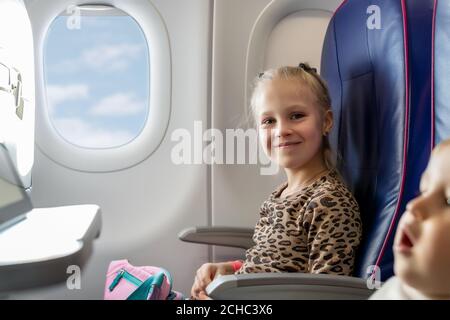 Paire de frères et sœurs adorables, petits et adorables, voyageant en avion. Garçon et fille assis à l'intérieur de l'avion pendant le vol. Enfants regardant des dessins animés Banque D'Images