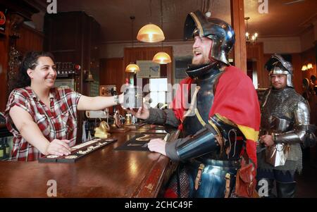 USAGE ÉDITORIAL SEULEMENT la barmaid Heba Khalil verse une pinte pour Sam Wall et Lewis Copson (à droite) à l'intérieur du pub du château de Warwick à Londres, pour célébrer le lancement de l'attraction Live les guerres des Roses qui commence au château de Warwick le 27 mai. Banque D'Images