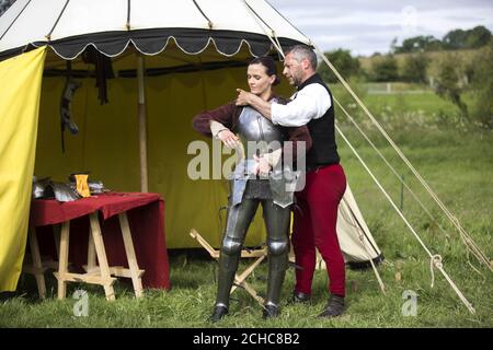 Adam Schuch-des Forges, maître de cour du patrimoine anglais, aide le médaillé d'or olympique Victoria Pendleton à sa protection avant d'apprendre à jouer dans le cadre du lancement de la saison médiévale des chevaliers du patrimoine anglais, au château de Kenilworth, dans le Warwickshire. Banque D'Images