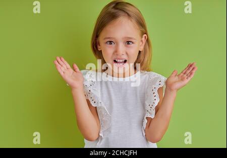 portrait de la petite fille surprise a étendu ses bras, en choc, isolé fond vert Banque D'Images