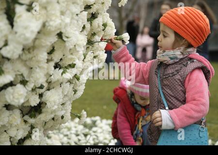 NOTE DE LA RÉDACTION: PERMISSION PARENTALE ACCORDÉE USAGE ÉDITORIAL SEULEMENT les enfants ajoutent des fleurs à une installation d'art intitulée 54k, qui est composé de 54,000 œillets blancs simples, au Potters Fields Park à Londres. La sculpture a été créée par maternité action pour souligner le nombre de femmes chaque année qui sont injustement contraintes de quitter leur emploi en raison de la grossesse et de la discrimination de la maternité au Royaume-Uni. Banque D'Images