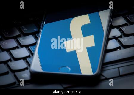 Le logo du site de réseau social Facebook est visible sur l'écran d'un smartphone reposant sur un clavier d'ordinateur portable. APPUYEZ SUR ASSOCIATION photo. Date de la photo: Dimanche 25 mars 2018. Le crédit photo devrait se lire comme suit : Dominic Lipinski/PA Wire Banque D'Images