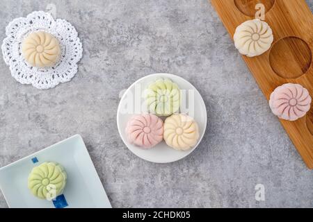 Gâteau de lune coloré en peau de neige, gâteau de lune sucré et enneigé, dessert traditionnel salé pour le festival de la mi-automne sur fond de ciment gris, vue du dessus Banque D'Images