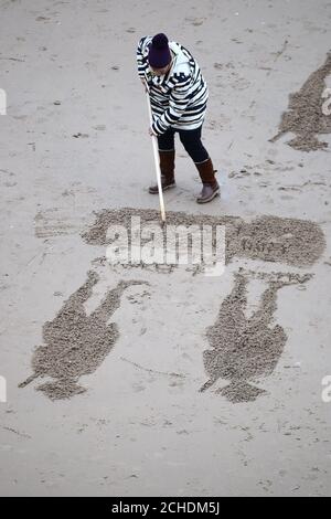 Les bénévoles de créer des dessins de plage sur les pages de la mer activité commémorative à Blackpool, sur le 100e anniversaire de la signature de l'Armistice qui a marqué la fin de la Première Guerre mondiale. Banque D'Images