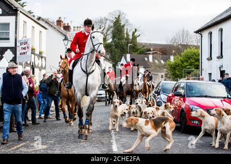 Le maître Huntsman mène les monticules et les cavaliers à travers main Street Crawfordsburn pendant la chasse du nouvel an Nord en bas à Crawfordsburn, en Irlande du Nord. Banque D'Images