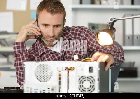 un jeune technicien répare l'ordinateur en atelier Banque D'Images