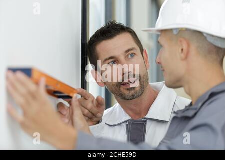 Deux homme mur holding spirit level Banque D'Images