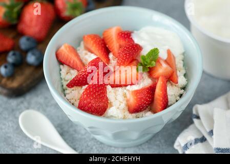 Fromage cottage avec fraises dans un bol en argile. Alimentation saine, diète, concept d'alimentation propre Banque D'Images