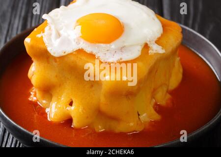 Délicieux grand sandwich chaud portugais Francesinha avec différents types de saucisses et de viande, servi avec du fromage avec de la sauce tomate à la bière et recouvert de Banque D'Images