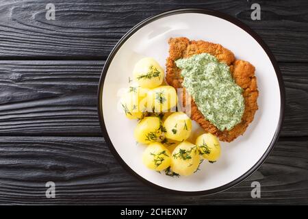 Délicieux schnitzel de cuisine allemande avec des pommes de terre neuves bouillies et la célèbre sauce verte de Francfort dans une assiette sur la table. Vue horizontale sur le dessus fr Banque D'Images