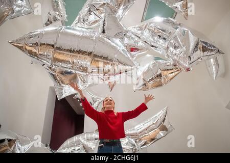 Un assistant de la galerie Tate Modern interagit avec l'installation de « Silver Clouds », lors d'une vue d'ensemble de la nouvelle exposition d'Andy Warhol à Tate Modern, Londres, qui présente des œuvres et des œuvres d'art pop classiques jamais présentées au Royaume-Uni. Photo PA. Date de la photo: Mardi 10 mars 2020. Le crédit photo devrait se lire comme suit : Dominic Lipinski/PA Wire Banque D'Images