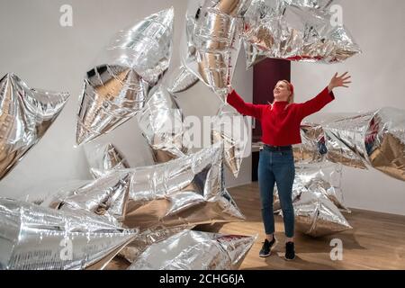 Un assistant de la galerie Tate Modern interagit avec l'installation de « Silver Clouds », lors d'une vue d'ensemble de la nouvelle exposition d'Andy Warhol à Tate Modern, Londres, qui présente des œuvres et des œuvres d'art pop classiques jamais présentées au Royaume-Uni. Photo PA. Date de la photo: Mardi 10 mars 2020. Le crédit photo devrait se lire comme suit : Dominic Lipinski/PA Wire Banque D'Images