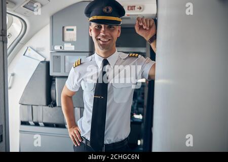 Homme gai capitaine debout à l'intérieur d'un avion commercial Banque D'Images