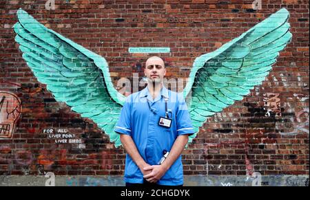 Michael Turner, infirmier praticien au Mersey Care NHS, se dresse devant les « Liver Bird Wings », une œuvre de Paul Curtis sur un mur dans le triangle Baltique de Liverpool. Banque D'Images