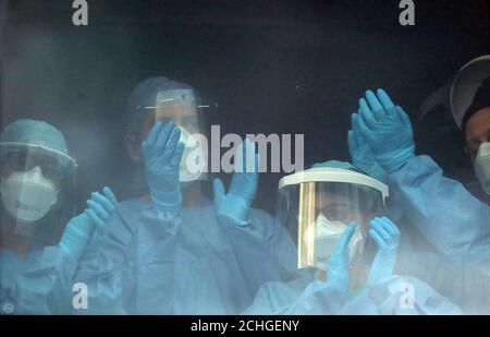 Le personnel infirmier se félicite en quelques minutes de la fenêtre de l'hôpital universitaire Queen Elizabeth de Glasgow, alors qu'il se joint aux applaudissements pour saluer les héros locaux du Clap national de jeudi pour que les soignants reconnaissent et soutiennent les travailleurs et les soignants du NHS qui luttent contre la pandémie de coronavirus. Banque D'Images
