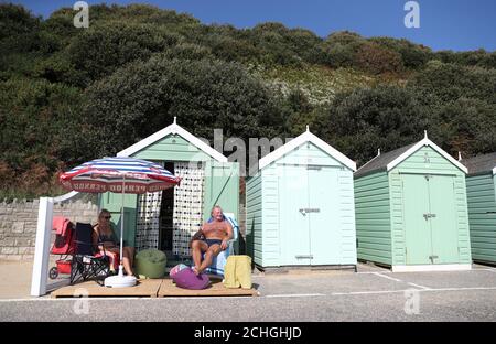 Rob Underhill (à droite) et sa femme Sally s'assoient à l'extérieur de leur cabane de plage pendant qu'ils profitent du soleil d'automne sur la plage de Bournemouth à Dorset. Banque D'Images