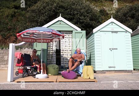 Rob Underhill (à droite) et sa femme Sally s'assoient à l'extérieur de leur cabane de plage pendant qu'ils profitent du soleil d'automne sur la plage de Bournemouth à Dorset. Banque D'Images