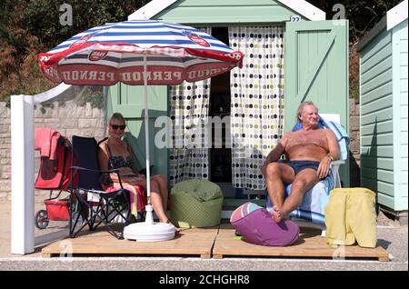 Rob Underhill (à droite) et sa femme Sally s'assoient à l'extérieur de leur cabane de plage pendant qu'ils profitent du soleil d'automne sur la plage de Bournemouth à Dorset. Banque D'Images