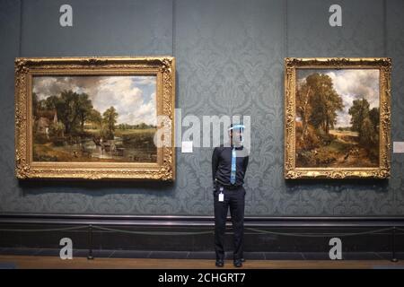 Un membre du personnel porte un pare-soleil tel qu'il est par le Hay Wain, 1821 ans, et le Cornfield, 1826 ans, par John Constable, Au National Portrait Gallery de Londres, alors qu'il se prépare à rouvrir après l'assouplissement des restrictions de confinement du coronavirus dans toute l'Angleterre. Banque D'Images