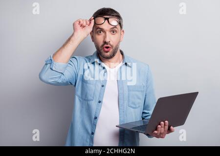 Gros plan portrait de son beau il s'est demandé choqué stupéfait un homme aux cheveux gris réussi géek en utilisant un ordinateur portable isolé sur un gris pastel Banque D'Images