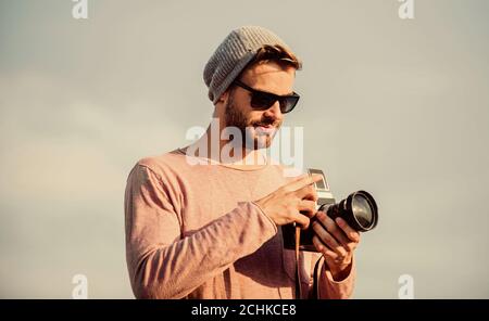 Des réglages manuels. Guy photographe en plein air fond de ciel. Journaliste de prendre photo. Hipster Le photojournaliste concept. Billet d'un blogueur. Photographe professionnel. Photographe guy beau appareil photo rétro. Banque D'Images