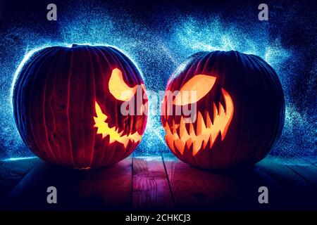 citrouilles d'halloween en face l'une de l'autre sur fond noir avec des lumières à pois en arrière-plan. Banque D'Images