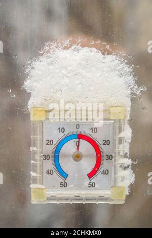 Thermometer in the form of a clock outside window with a snow cap Banque D'Images