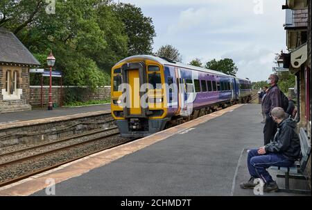 Les passagers portant des masques observant l'arrivée du service de chemin de fer du Nord à Leeds à 48:17, sur la plate-forme de Horton en direction du sud, à la gare de Ribblesdale. Banque D'Images