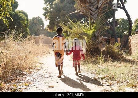 Deux enfants africains marchent sur la route naturelle dans le village africain Banque D'Images