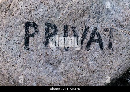 Bloc erratique de granit lumineux avec l'inscription décolorée privé à marquer l'extrémité de la zone publique Banque D'Images