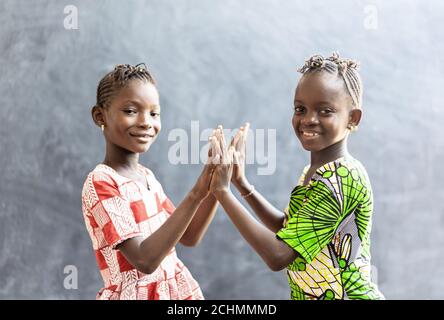 Photo franche de deux sœurs africaines enfants filles femmes jouant Sourire aux mains et au visage Banque D'Images