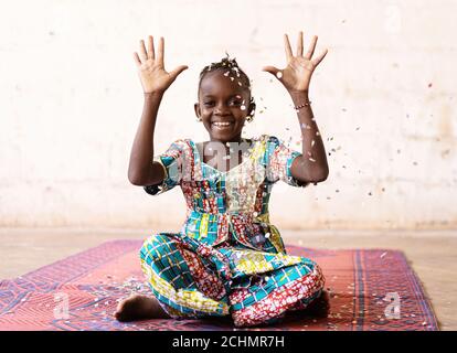 African Fun Party Girl, femme souriante jetant des confetti, sur fond blanc avec Copy Space Banque D'Images