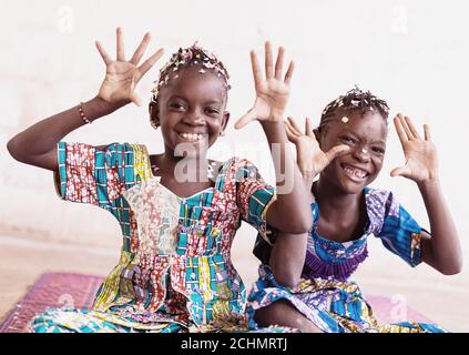 De vraies filles africaines qui se amusent à jeter des confetti à leur Mains dans une salle blanche Banque D'Images