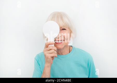 Femme âgée ayant un examen oculaire avec une couverture oculaire à l'aide d'un outil spécial, sur fond blanc. Test oculaire patient âgé. Concept de test de vision Banque D'Images