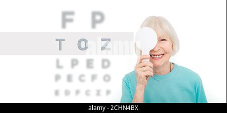 Femme âgée ayant un examen oculaire avec une couverture oculaire à l'aide d'un outil spécial, sur fond blanc. Test oculaire patient âgé Banque D'Images