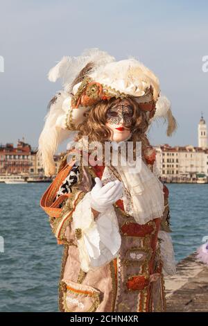 Venise, Vénétie, italie - homme en costume classique au Carnaval de Venise posant au coucher du soleil avec la lagune et San Marco derrière lui Banque D'Images