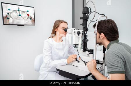 La femme médecin de l'œil fait un examen de vision diagnostique homme adulte. Examen des yeux et diagnostic des maladies oculaires Banque D'Images