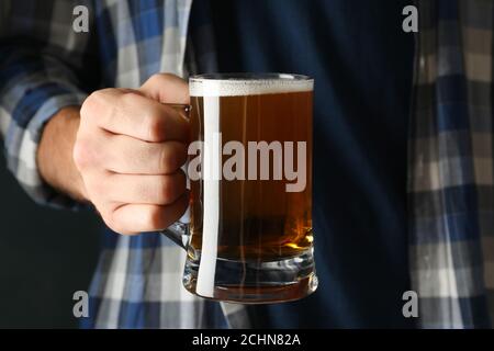 Un homme en chemise à carreaux tient un verre de bière Banque D'Images