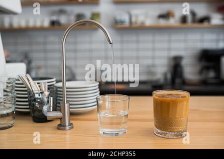 de l'eau coule d'un robinet dans un verre Banque D'Images