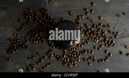 Tasse de café en papier avec grains de café rôtis sur fond de table en bois. Tasse de café noir. Banque D'Images