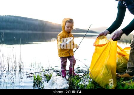 Père avec petite fille collectant des déchets à l'extérieur dans la nature, plugging concept. Banque D'Images