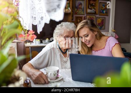 Petite-fille adulte enseignant à sa grand-mère âgée d'utiliser un ordinateur portable Banque D'Images
