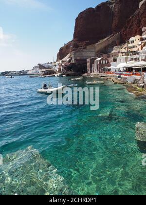 Bateaux amarrés dans la mer claire de la baie d'Amoudi contre ciel bleu clair, Oia, Santorini Banque D'Images