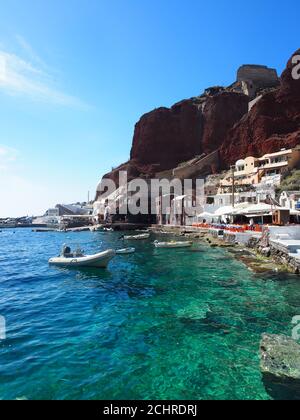 Bateaux amarrés dans la mer claire de la baie d'Amoudi contre ciel bleu clair, Oia, Santorini Banque D'Images