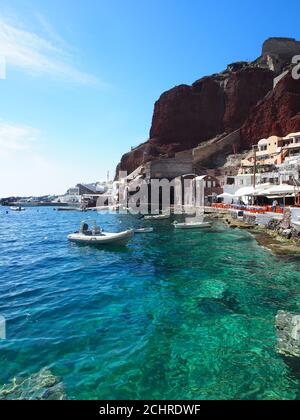 Bateaux amarrés dans la mer claire de la baie d'Amoudi contre ciel bleu clair, Oia, Santorini Banque D'Images